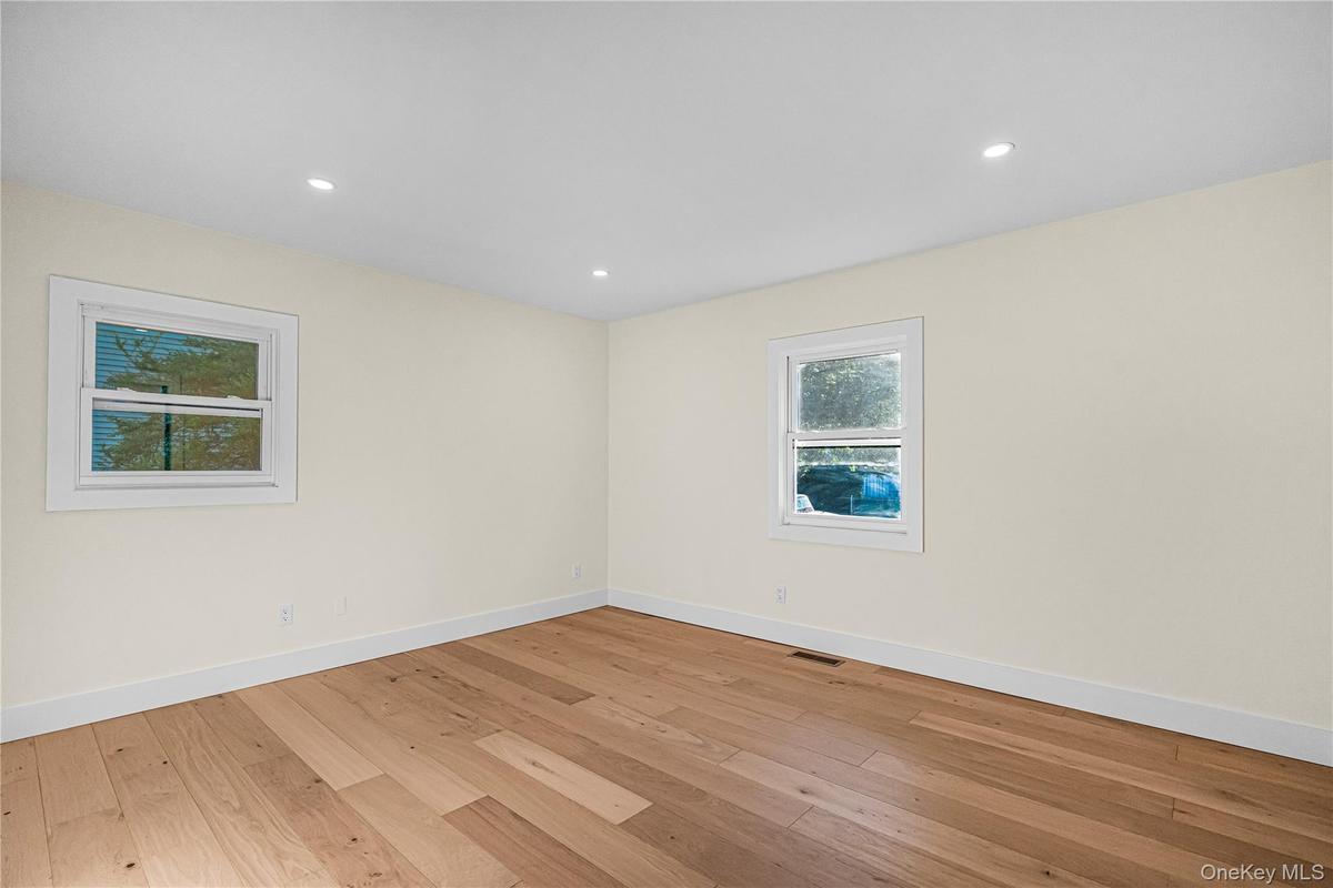 Room featuring warm-toned wood-finish flooring, light-colored walls, and recessed ceiling lighting