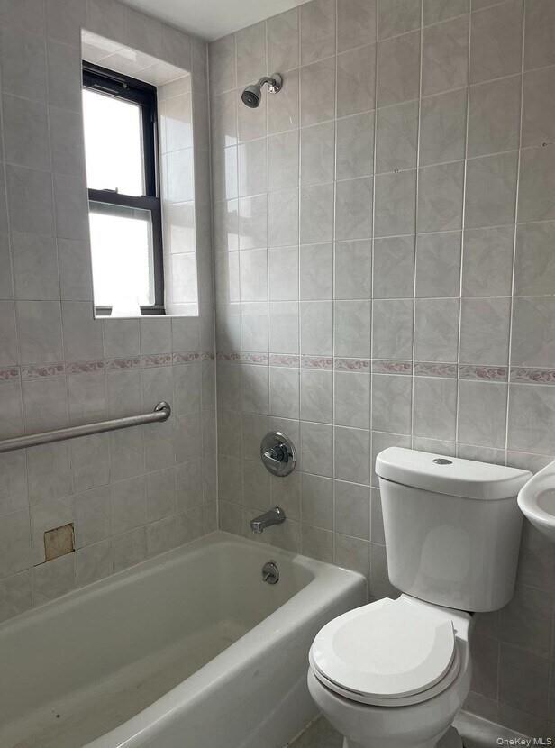 Full bathroom with shower / tub combination and tile walls