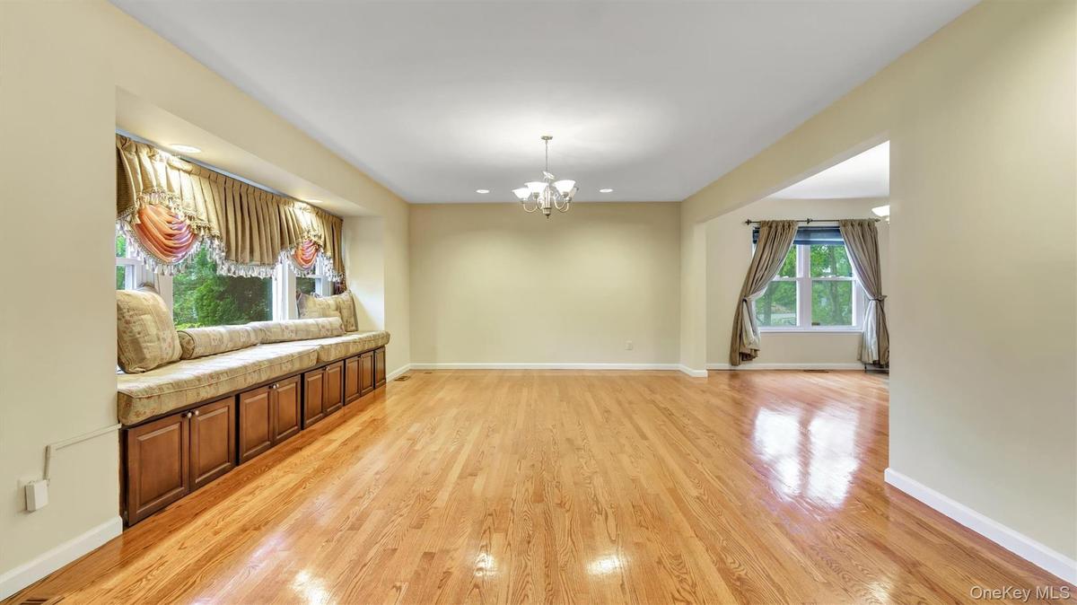 Unfurnished living room featuring light wood finished floors, a chandelier, baseboards, and recessed lighting