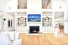 Living area featuring hardwood / wood-style flooring, a glass covered fireplace, high vaulted ceiling, and built in shelves