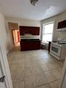 Kitchen featuring stove, reddish brown cabinets, tasteful backsplash, dark countertops, and range hood