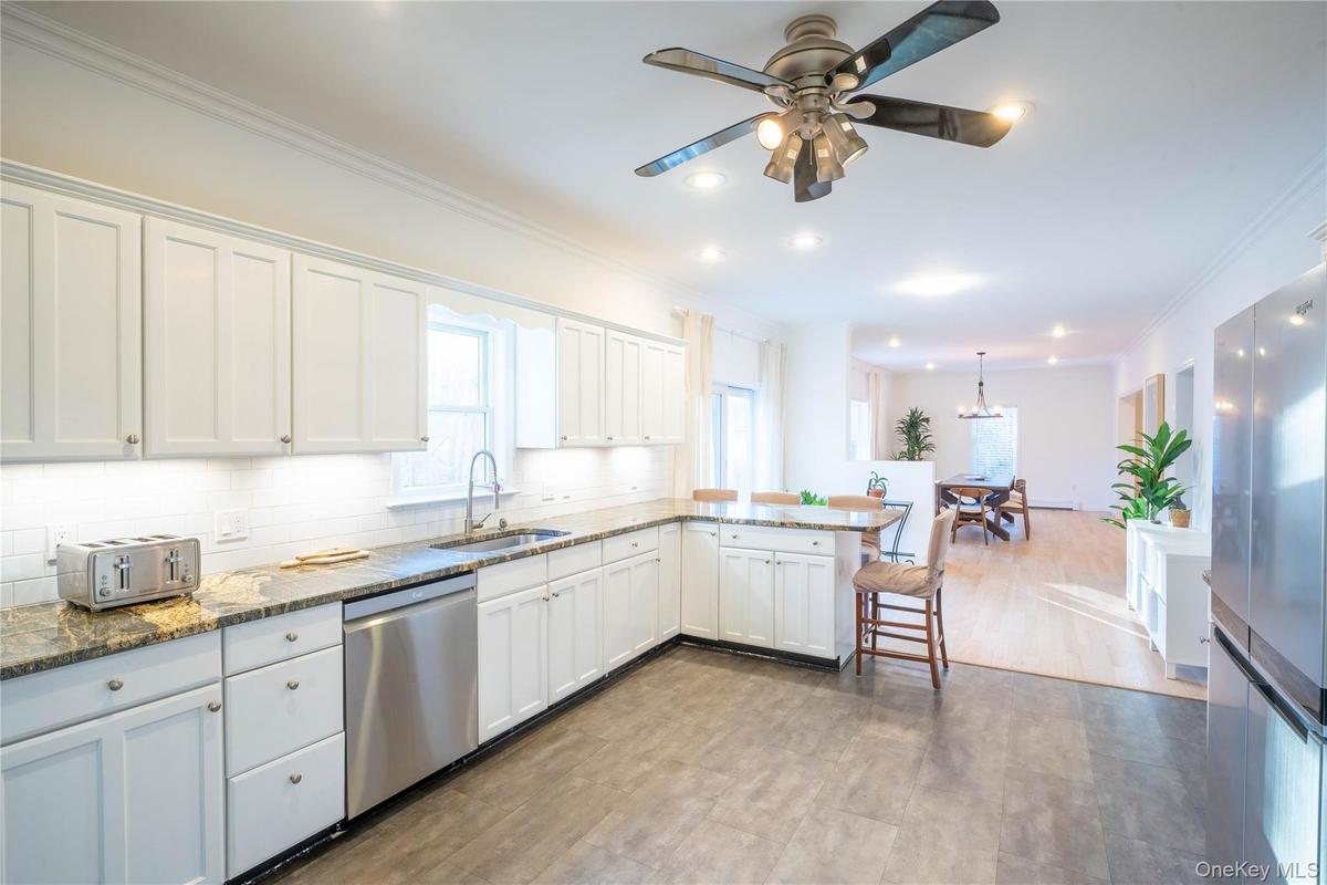 Kitchen with decorative backsplash, white cabinets, dishwasher, a peninsula, and a sink