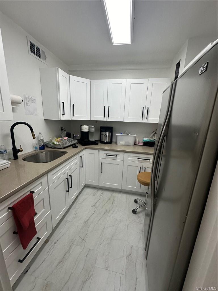 Kitchen with refrigerator, sink, and white cabinetry