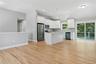 The spacious kitchen features a large center island, quartz countertops, white soft-close cabinets, and a complete stainless steel appliance package .