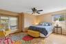 Bedroom featuring multiple windows, wood finished floors, a baseboard radiator, and ceiling fan