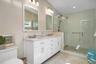 Full bath featuring double vanity and a stall shower