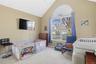 First Floor ,vaulted ceiling, arched window with blind, carpeted flooring, and neutral wall tones