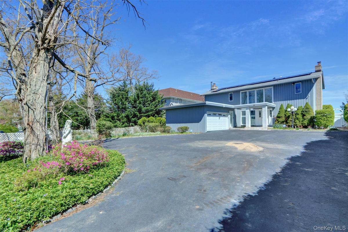 Traditional-style home with a chimney, roof mounted solar panels, asphalt driveway, and an attached garage