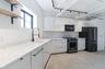 Kitchen featuring black appliances, tasteful backsplash, modern cabinets, and white cabinets