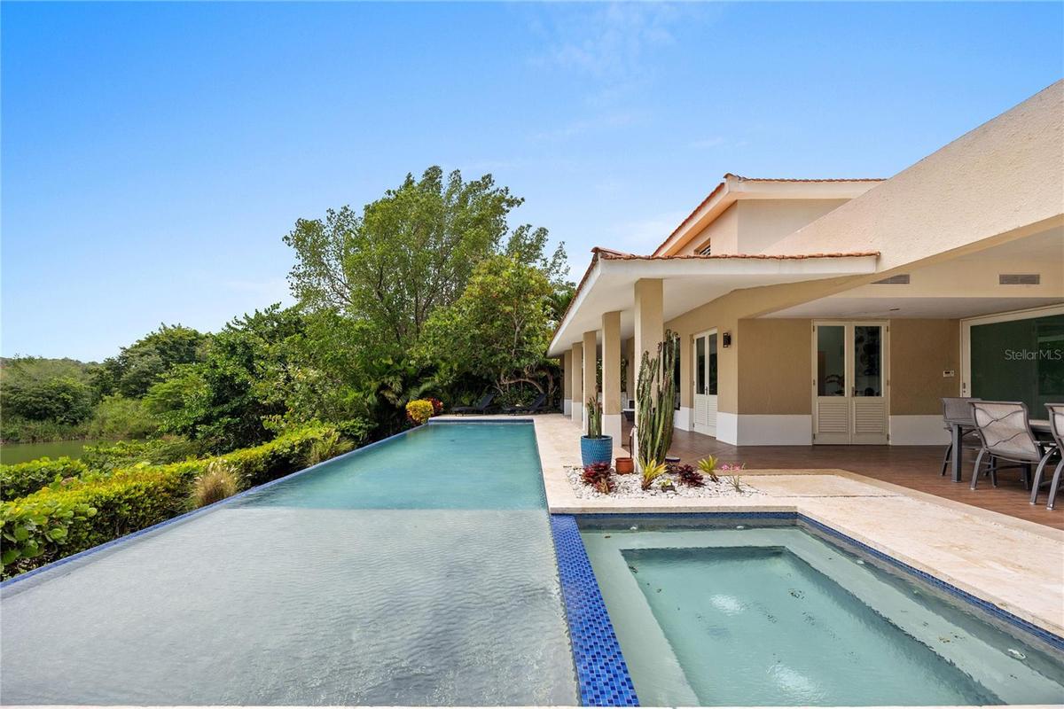 The main living areas flow seamlessly into the outdoor spaces, where a wraparound covered terrace invites year-round enjoyment. Surrounded by lush lan