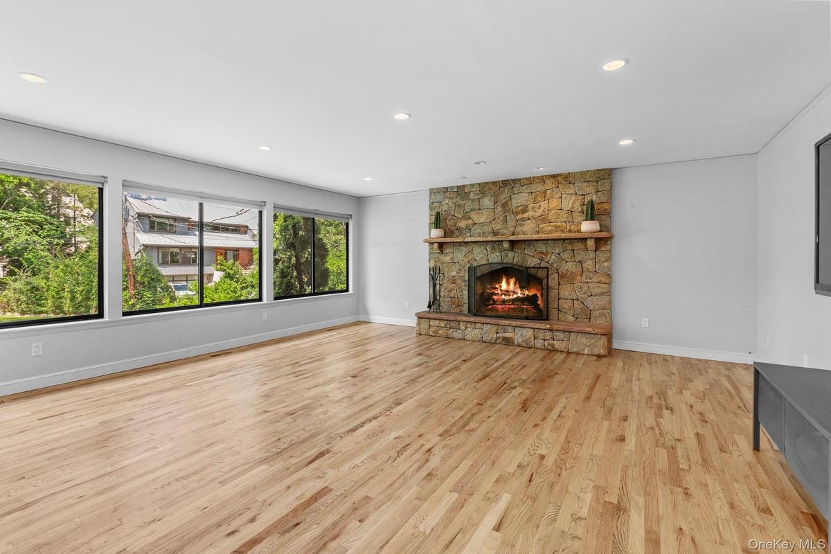 Unfurnished living room featuring baseboards, a fireplace, light wood-style floors, and recessed lighting
