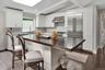 Kitchen featuring stainless steel built in fridge, dark wood finished floors, white cabinets, ventilation hood, and a breakfast bar area