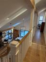 Corridor featuring healthy amount of natural light, lofted ceiling, a chandelier, and light wood-style flooring