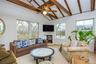 Living room featuring healthy amount of natural light, a glass covered fireplace, ceiling fan, and light wood-type flooring