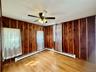 2 - Empty room with wooden walls, wood finished floors, and a ceiling fan