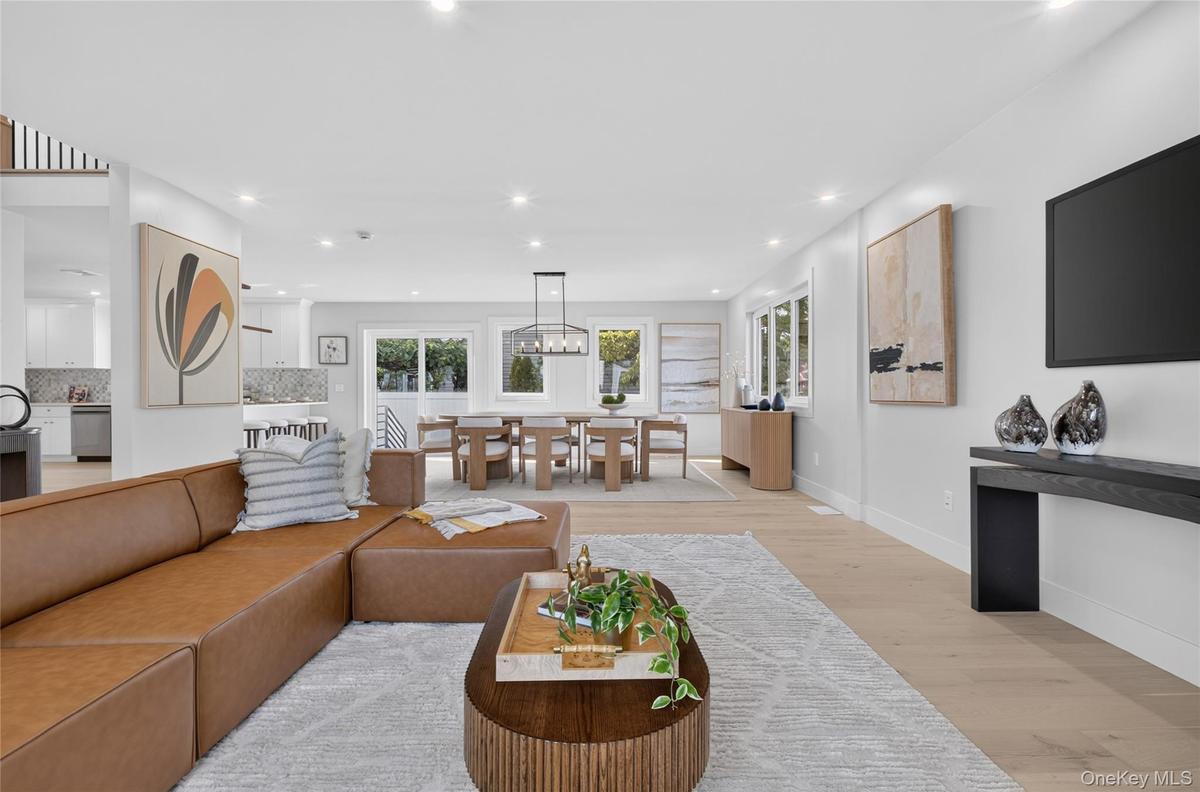 Open-concept living area with light wood-finish flooring, recessed lighting, and expansive windows