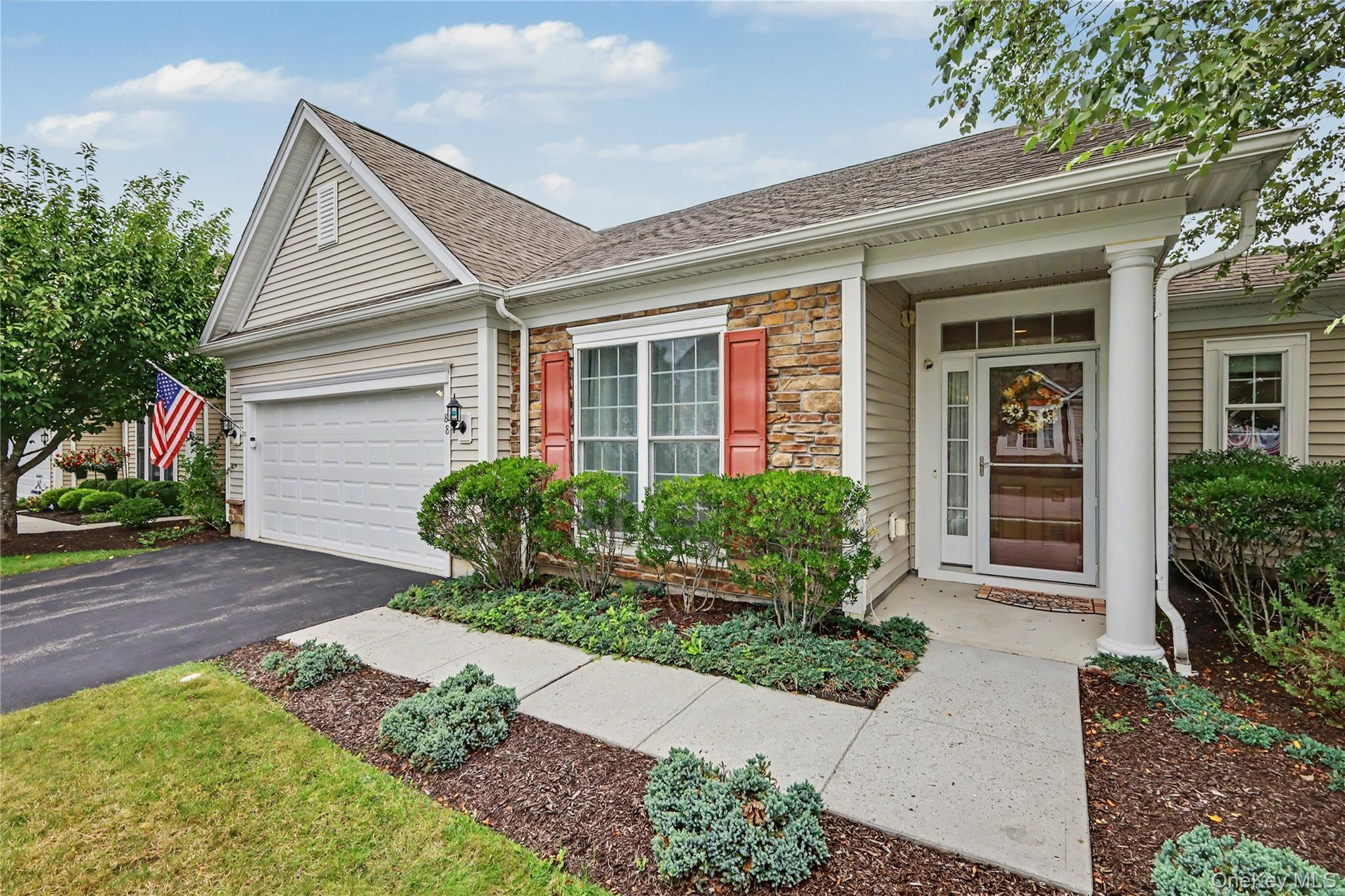 Stone facade accents, attached garage, covered entryway, detailed front door, and mature landscaping