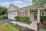 Stone facade accents, attached garage, covered entryway, detailed front door, and mature landscaping