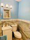 Full bath with tile walls, vanity, toilet, an enclosed shower, and a wainscoted wall