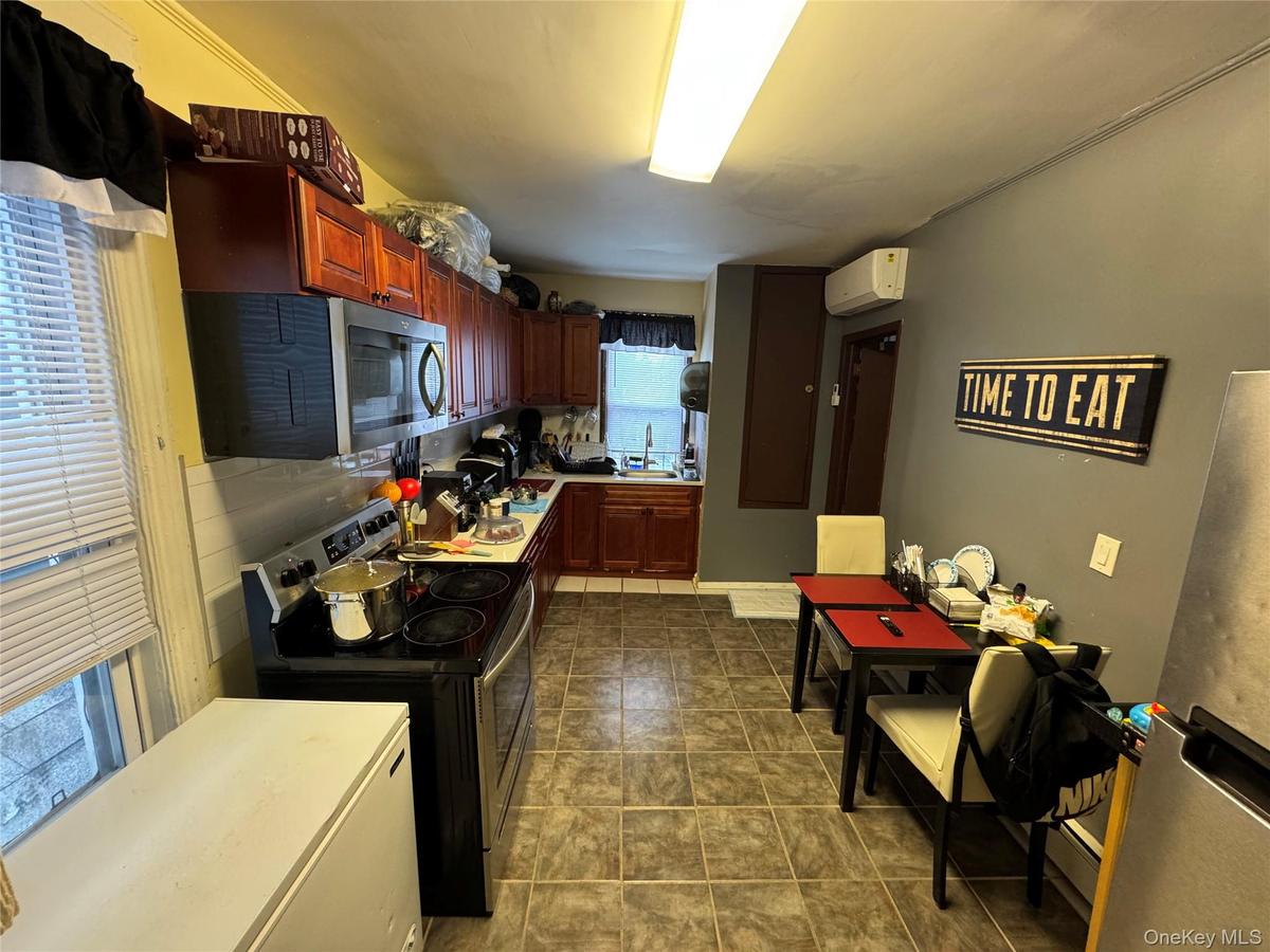 Kitchen featuring light countertops, a sink, stainless steel appliances, an AC wall unit, and dark brown cabinets