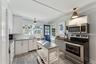 Kitchen featuring stainless steel appliances, crown molding, hanging light fixtures, white cabinetry, and light wood finished floors
