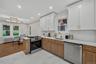 Contemporary kitchen featuring white shaker upper cabinetry and wood-finish lower cabinetry with gold-tone hardware
