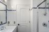 Bathroom featuring white tiled walls with a blue accent band, a glass-enclosed shower, and a vanity with an integrated sink and chrome faucet