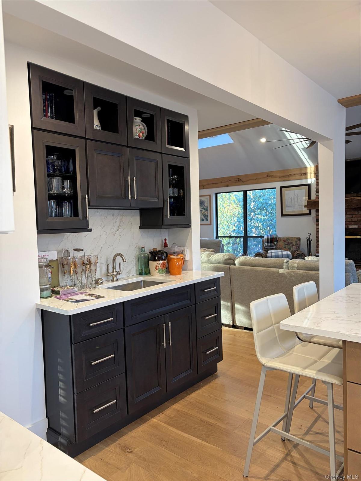 Kitchen featuring glass insert cabinets, light stone countertops, backsplash, open floor plan, and recessed lighting