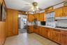 Kitchen featuring light countertops, light tile patterned floors, ceiling fan, brown cabinets, and radiator heating unit