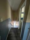 Corridor with baseboards and a high ceiling