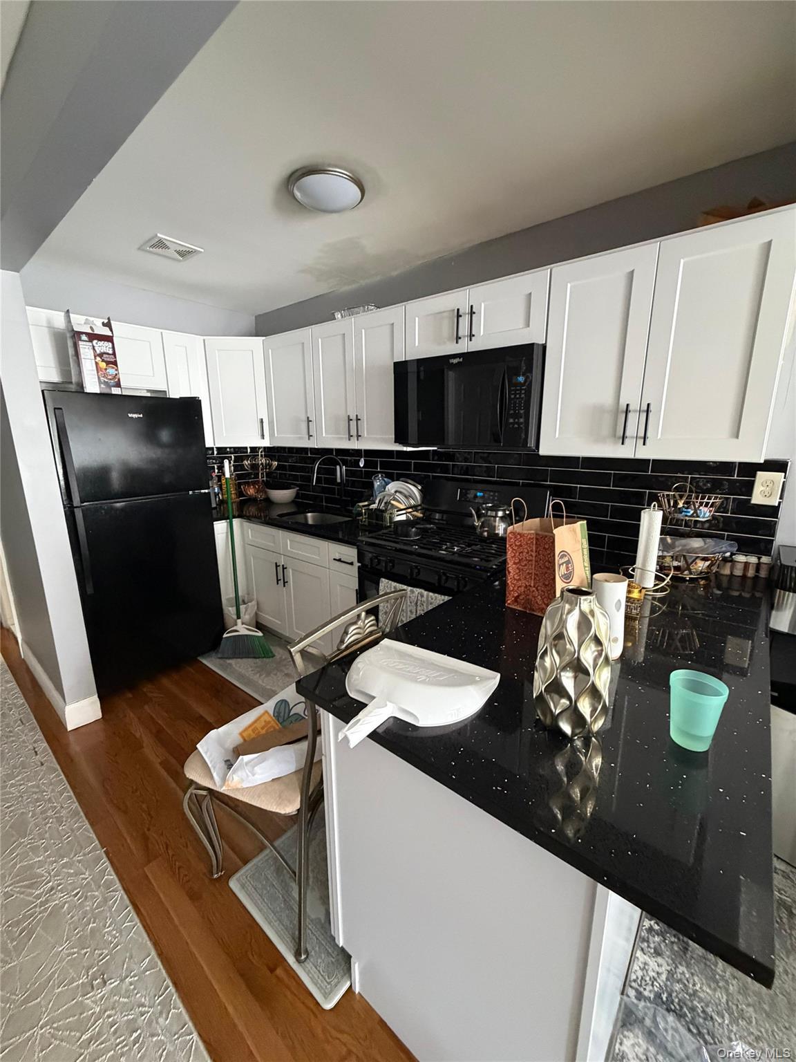 Kitchen featuring white shaker-style cabinetry with matte black hardware, a black subway tile backsplash, and black appliances