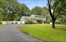 Traditional-style house with driveway, an attached garage, and view of scattered trees