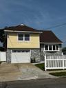 View of front of house with stone siding, an attached garage, driveway, and a shingled roof