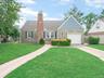 Stone and siding exterior with a prominent brick chimney, attached garage, and a paver walkway