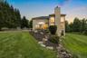 Rear exterior featuring multiple large windows, a stone-accented outdoor patio, and a dedicated outdoor cooking area