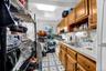 Kitchen with brown cabinetry, light countertops, light floors, white range, and open shelves