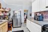 Kitchen with freestanding refrigerator, crown molding, light countertops, white cabinets, and backsplash