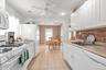 Kitchen featuring white appliances, white cabinetry, light countertops, decorative backsplash, and light tile patterned flooring