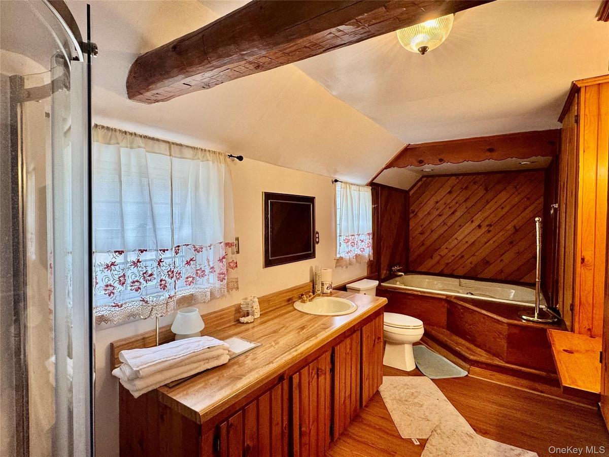 0 - master Bathroom with vanity, lofted ceiling, toilet, a garden tub, and wood finished floors