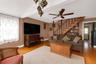 Living area featuring hardwood flooring, a built-in staircase with balusters, recessed built-in shelving, and a ceiling fan