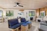 Living area with wood-finish flooring, a light wood-paneled ceiling, and a black ceiling fan