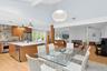 Dining room with light wood-style floors, beam ceiling, a fireplace, beverage cooler, and high vaulted ceiling