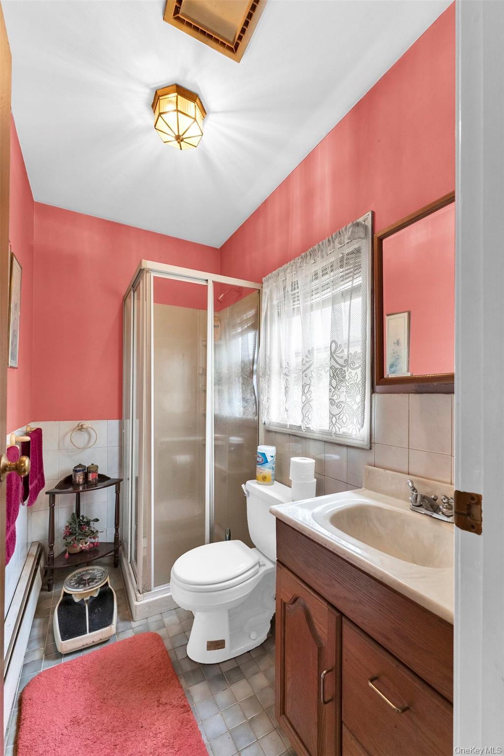 Bathroom featuring a shower stall with sliding glass doors, a vanity with a built-in sink, and a toilet