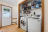 Dedicated laundry area featuring a full-size washer and dryer hookup, wire shelving, and wood-finish flooring