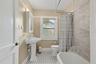 The full bathroom blends vintage character with thoughtful updates, including classic tilework, a pedestal sink, and a tub/shower combination.