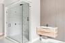 Spacious glass-enclosed shower with herringbone pattern tile accent wall and integrated niche