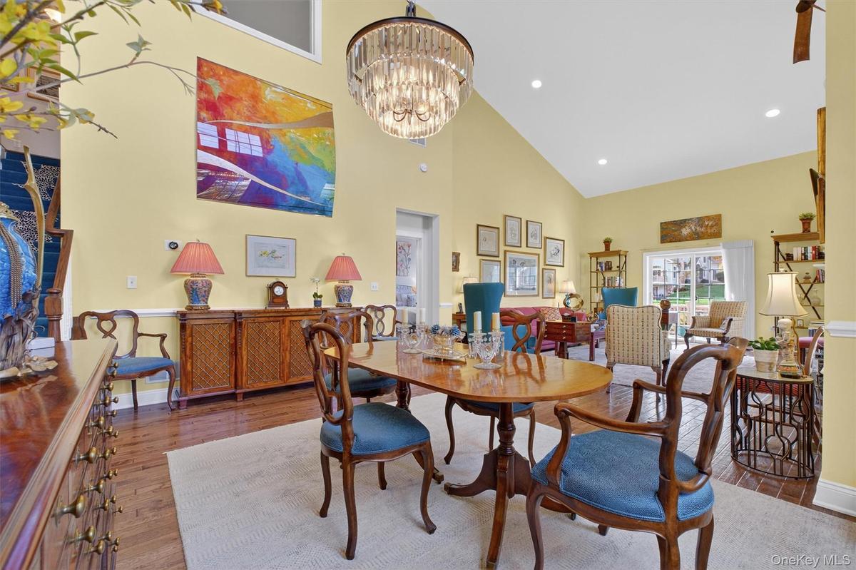 Dining area featuring high vaulted ceiling, wood finished floors, recessed lighting, and a chandelier