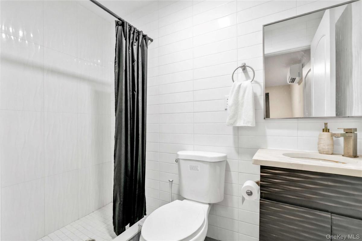 Bathroom with vanity, a shower stall, and tile walls