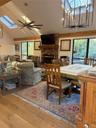 Dining area with a skylight, a ceiling fan, light wood-style flooring, suspended lighting, and a brick fireplace