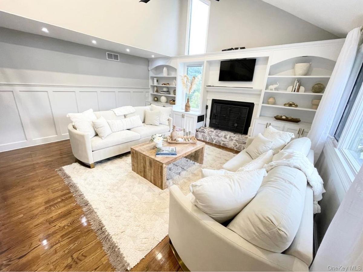 Living area featuring wood finished floors, high vaulted ceiling, a glass covered fireplace, a decorative wall, and recessed lighting
